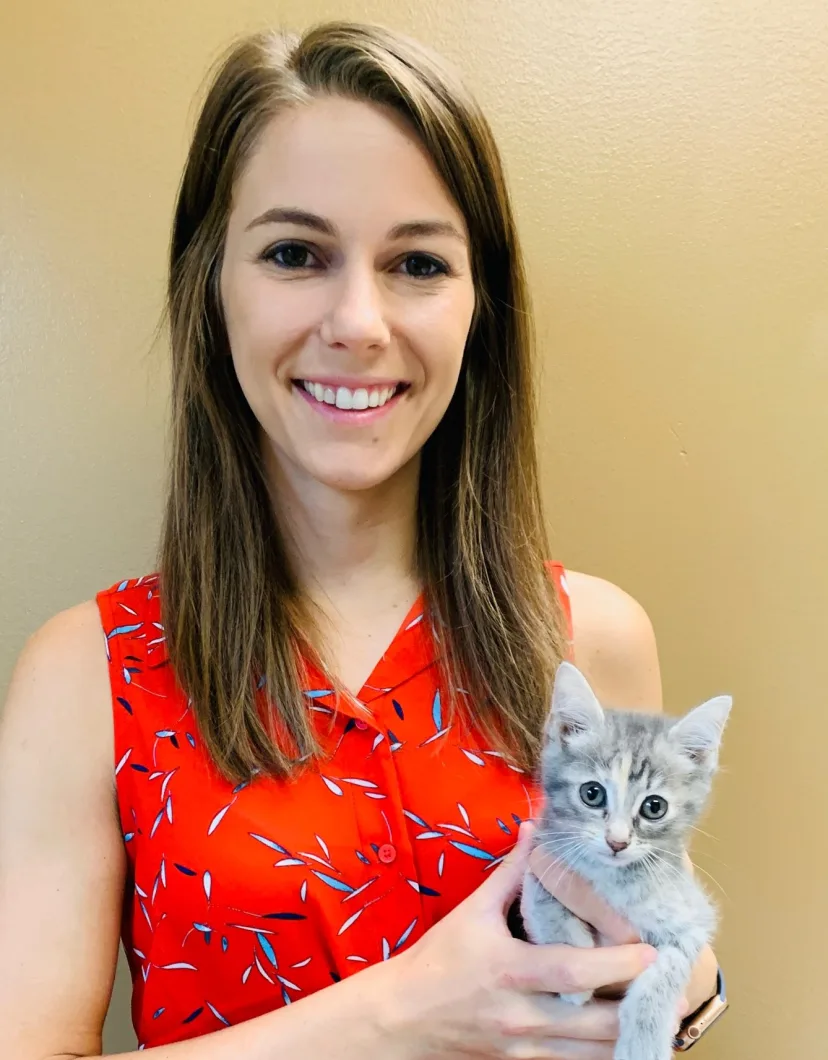 Dr. Ashley Flautt smiling at the camera while holding a cat